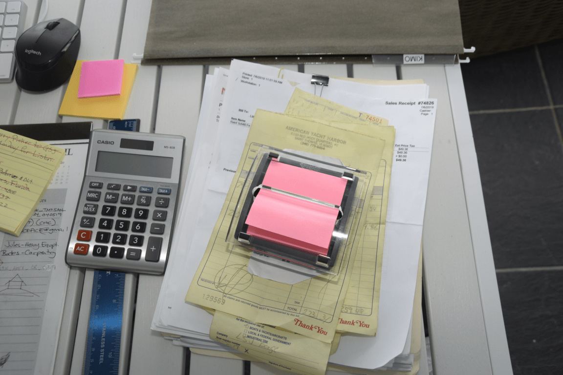 A calculator and coins on a desk beside written notes.
